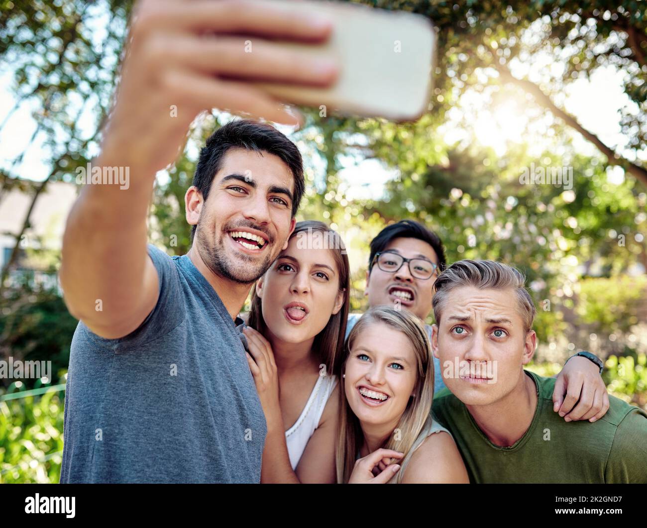 Preservare il momento. Scatto corto di un giovane gruppo di amici che prendono selfie mentre si godono un paio di bevande all'aperto al sole estivo. Foto Stock