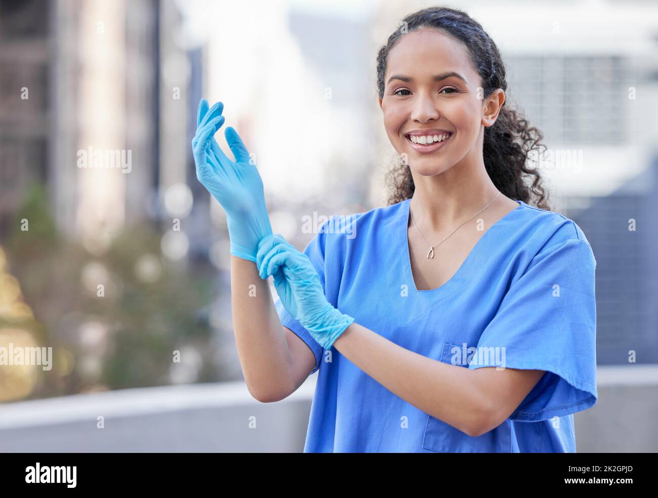 Prepararsi per un controllo. Shot di una giovane dottore donna che indossa guanti contro uno sfondo cittadino. Foto Stock