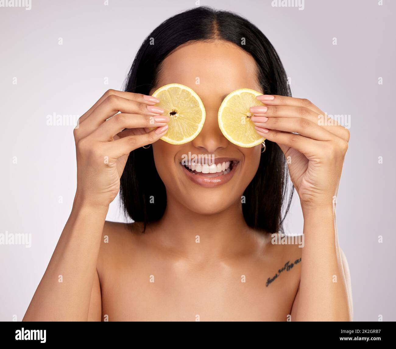 I trattamenti naturali funzionano davvero. Studio girato di una giovane donna attraente in posa con fette di limone sopra i suoi occhi su uno sfondo rosa. Foto Stock