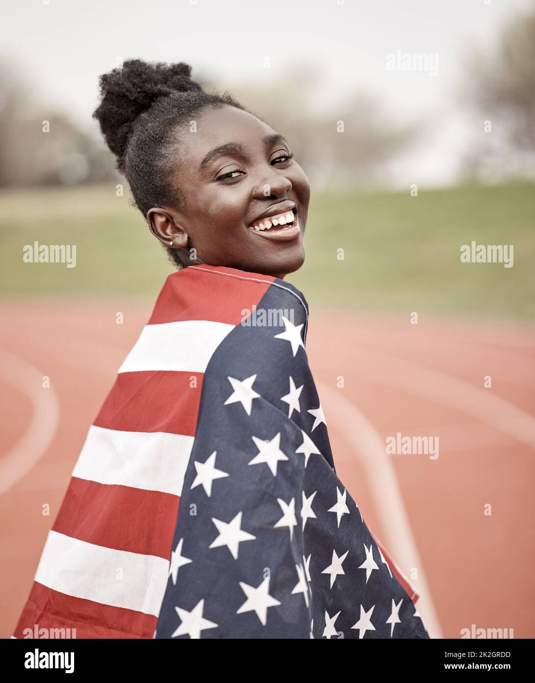 Youre guardando una stella che si accira. Scatto di una bella giovane atleta femminile con la bandiera americana avvolta intorno a se stessa. Foto Stock