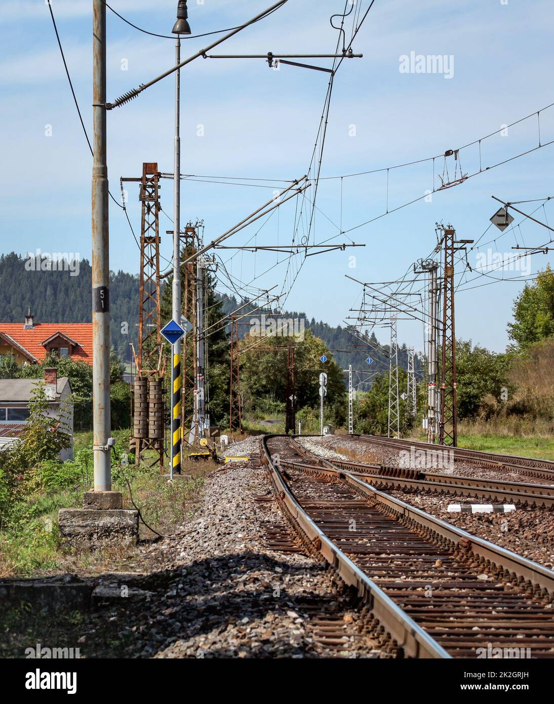 Svuotare i binari ferroviari su una soleggiata giornata estiva, in zona rurale, pilastri con molti cavi elettrici intorno a. Foto Stock
