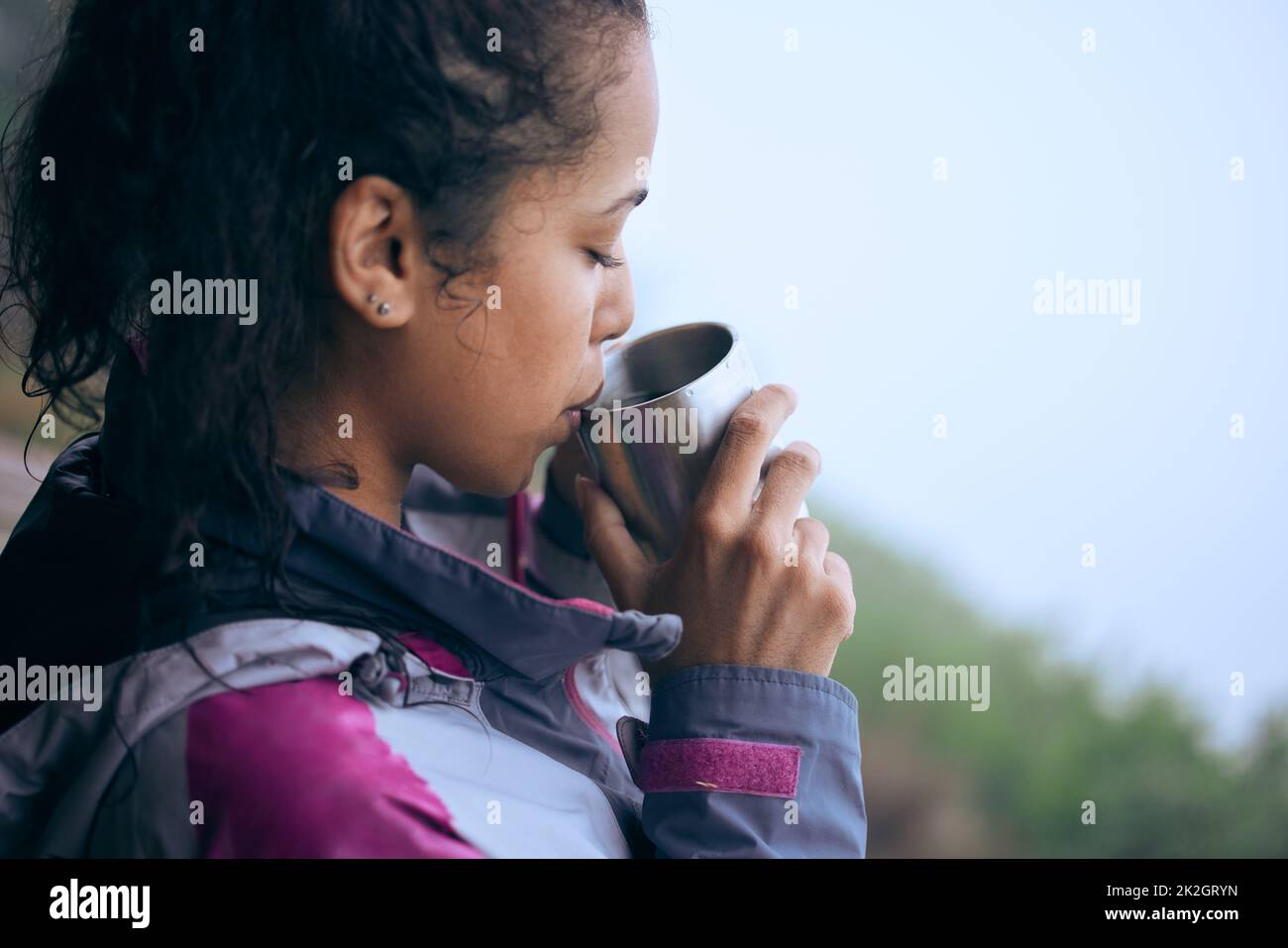 Le pause caffè sono necessarie durante le escursioni mattutine. Un colpo corto di una giovane donna attraente che beve caffè mentre fa una pausa durante la sua escursione di mattina presto. Foto Stock
