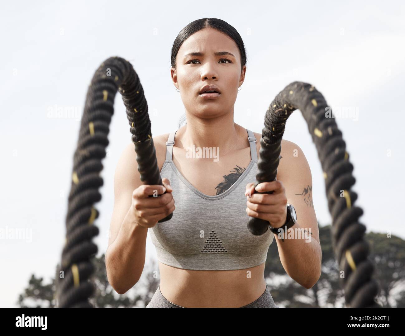 Lavorare sodo, rimanere coerenti ed essere pazienti. Sparato di una giovane donna atletica che fa l'addestramento pesante della corda fuori. Foto Stock