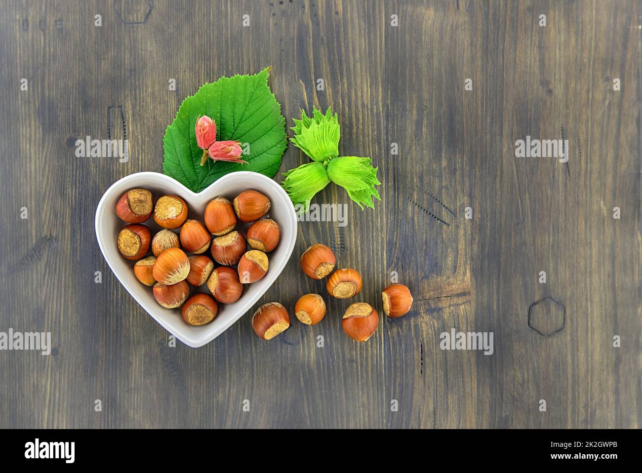Nocciole fresche non sgusciate in un piatto a forma di cuore Foto Stock