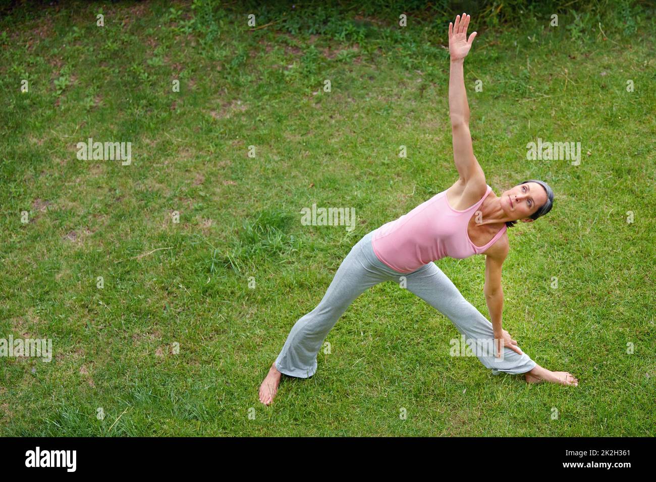 Esercizio rilassante. Scatto di una donna matura che fa la posa estesa del triangolo yoga all'aperto. Foto Stock
