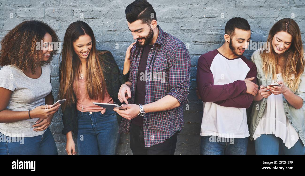 Buoni amici e un'ottima connessione wifi. Foto di un gruppo di giovani amici che utilizzano i loro dispositivi wireless all'aperto. Foto Stock