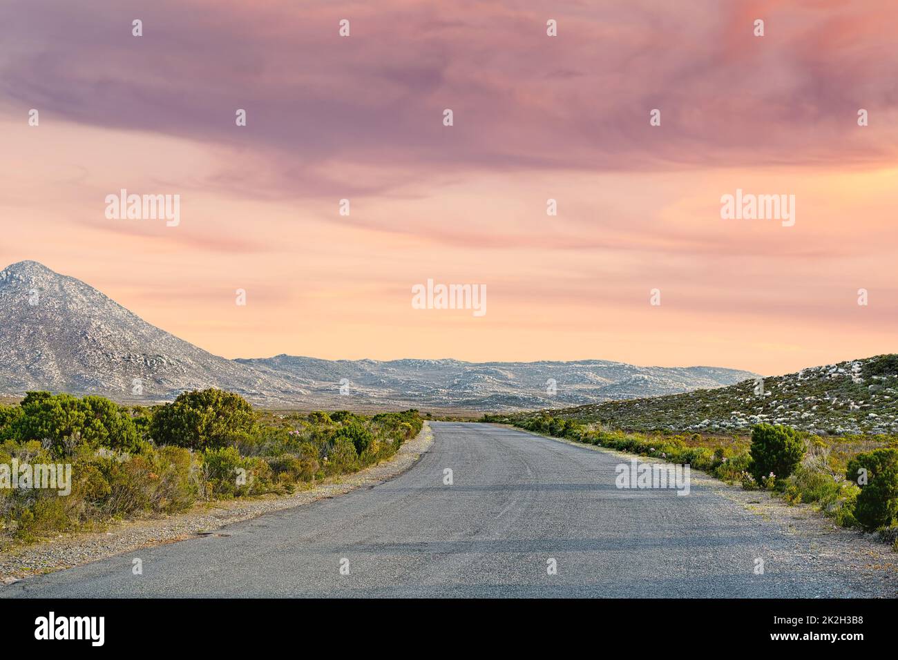 Bei viaggi. Una strada di campagna che si standa attraverso un paesaggio pittoresco. Foto Stock