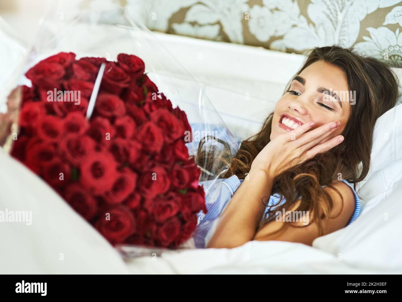 Che sorpresa. Scatto corto di una giovane donna attraente che guarda sorpreso dopo il risveglio fino ad un bouquet di rose. Foto Stock