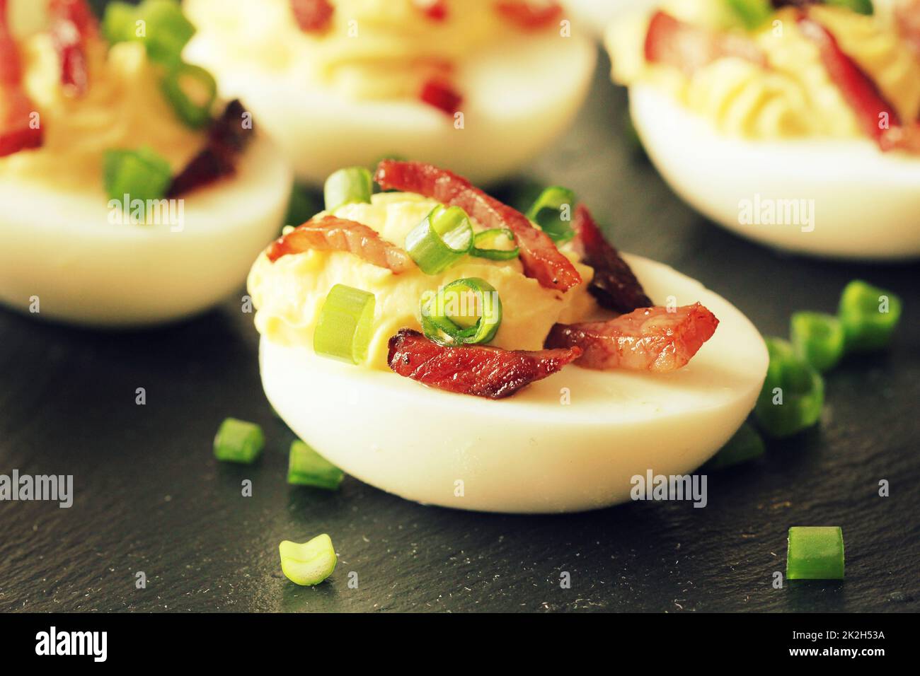Uova ripiene con pancetta su sfondo nero Foto Stock