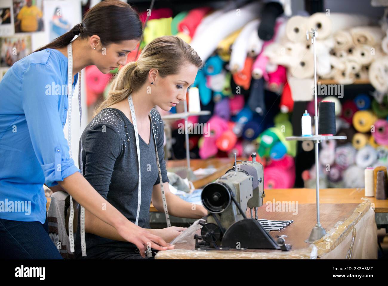 Tutto deve essere perfetto. Due donne che lavorano su un abito in un banco da lavoro all'interno del loro negozio di tessuti. Foto Stock