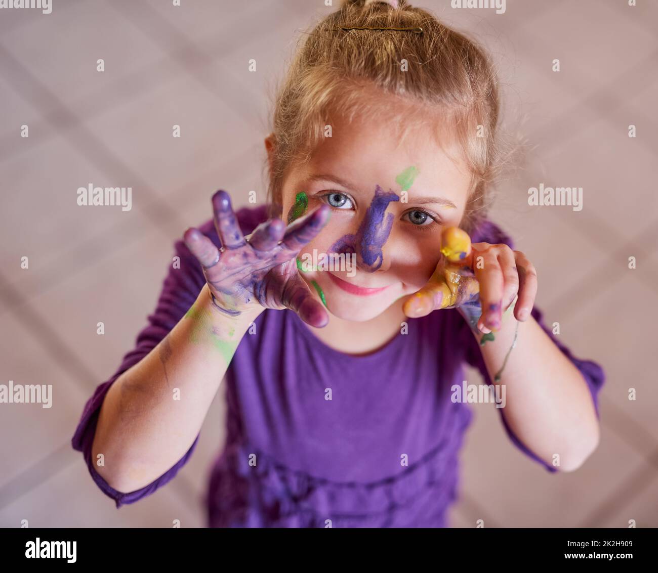 Diventare l'arte ritratto ritagliato di una bambina con le mani e il volto coperto di vernice. Foto Stock