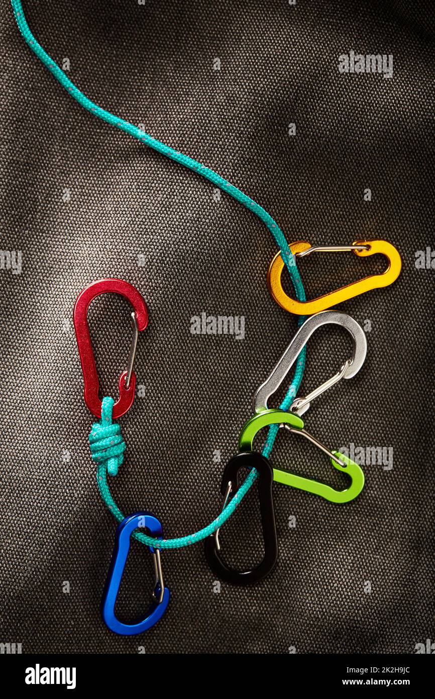 accessori per moschettoni colorati su una piccola corda turchese con illuminazione a tasti bassi. Questo attrezzo non è adatto per arrampicarsi Foto Stock
