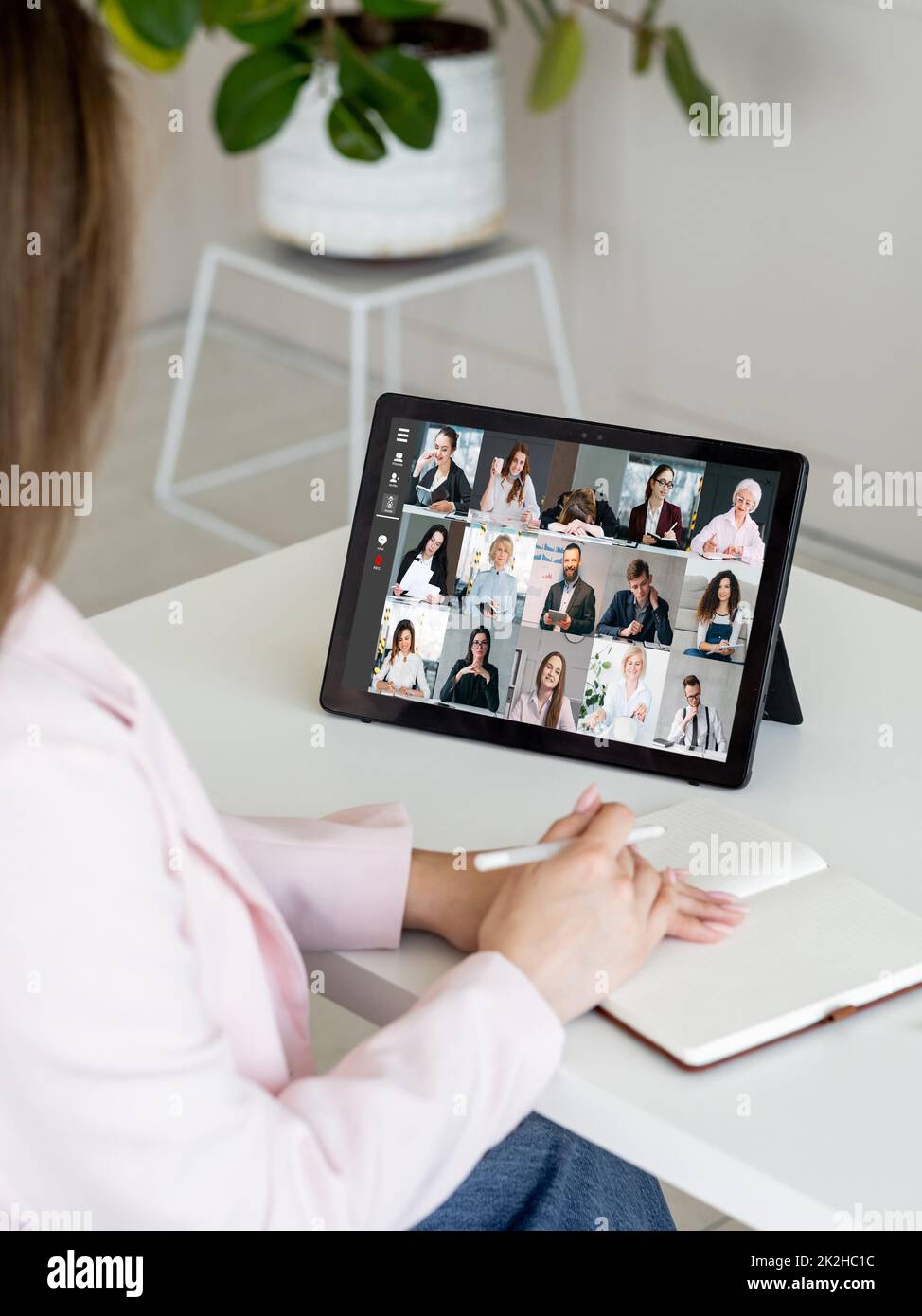 Teleconferenza del team aziendale. Riunione remota. Cooperazione virtuale. Dipendente femminile che utilizza un tablet per lavorare online con i colleghi sullo schermo in digitale di Foto Stock