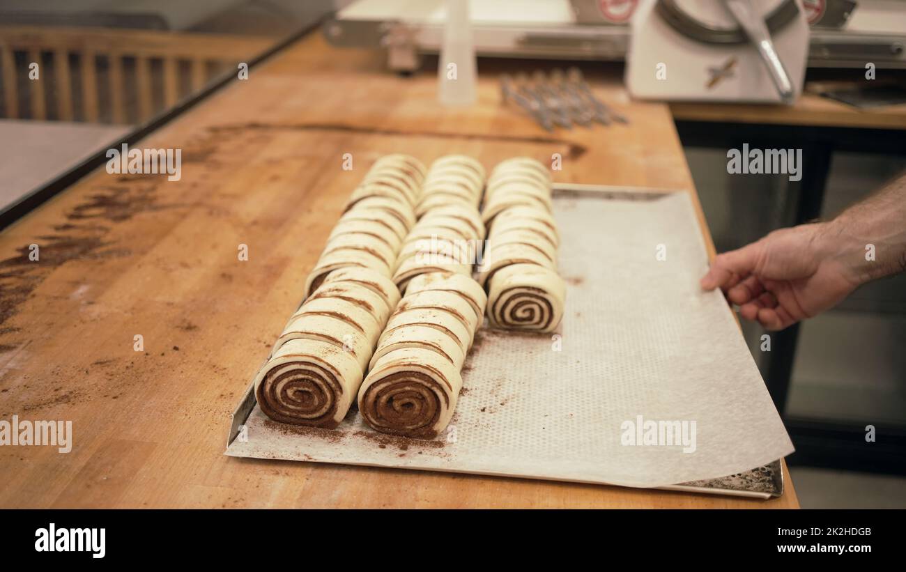 Panettiere che lavora con dolci fatti a mano in una piccola panetteria. Foto Stock