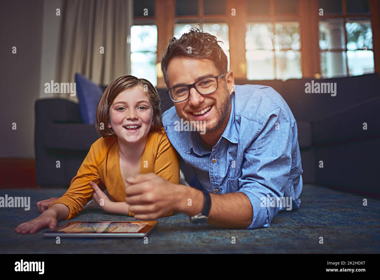 La mia bambina ama questa tecnologia. Girato di un padre e una figlia che si trovano sul pavimento e usando un tablet digitale insieme a casa. Foto Stock