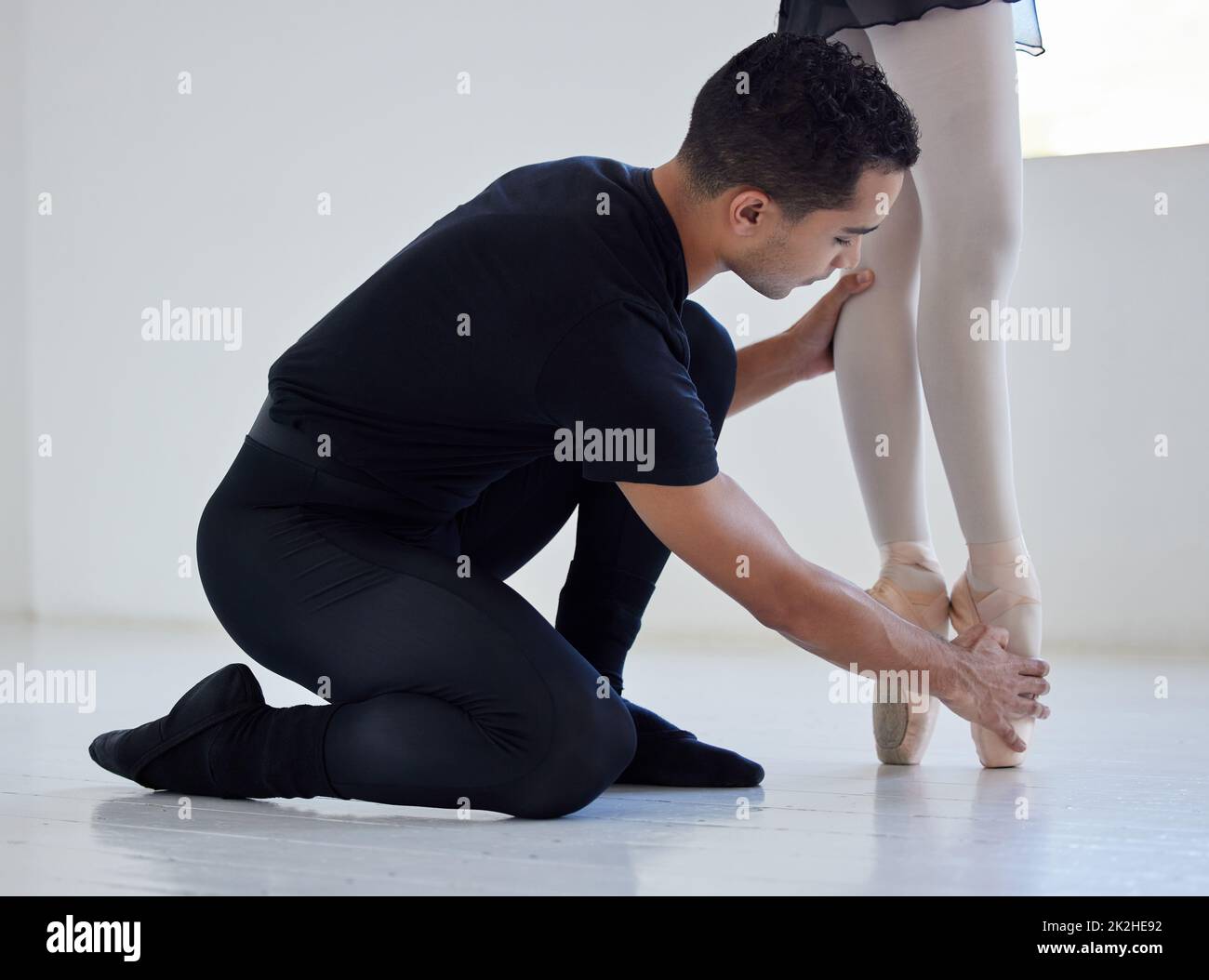 Dovete stare così. Primo piano di un insegnante di balletto che assiste uno studente con la sua posizione in uno studio di danza. Foto Stock