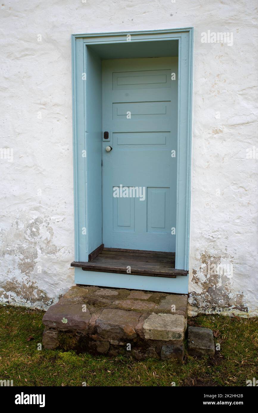 Porta in legno coloniale blu in cottage di pietra imbiancata Foto Stock
