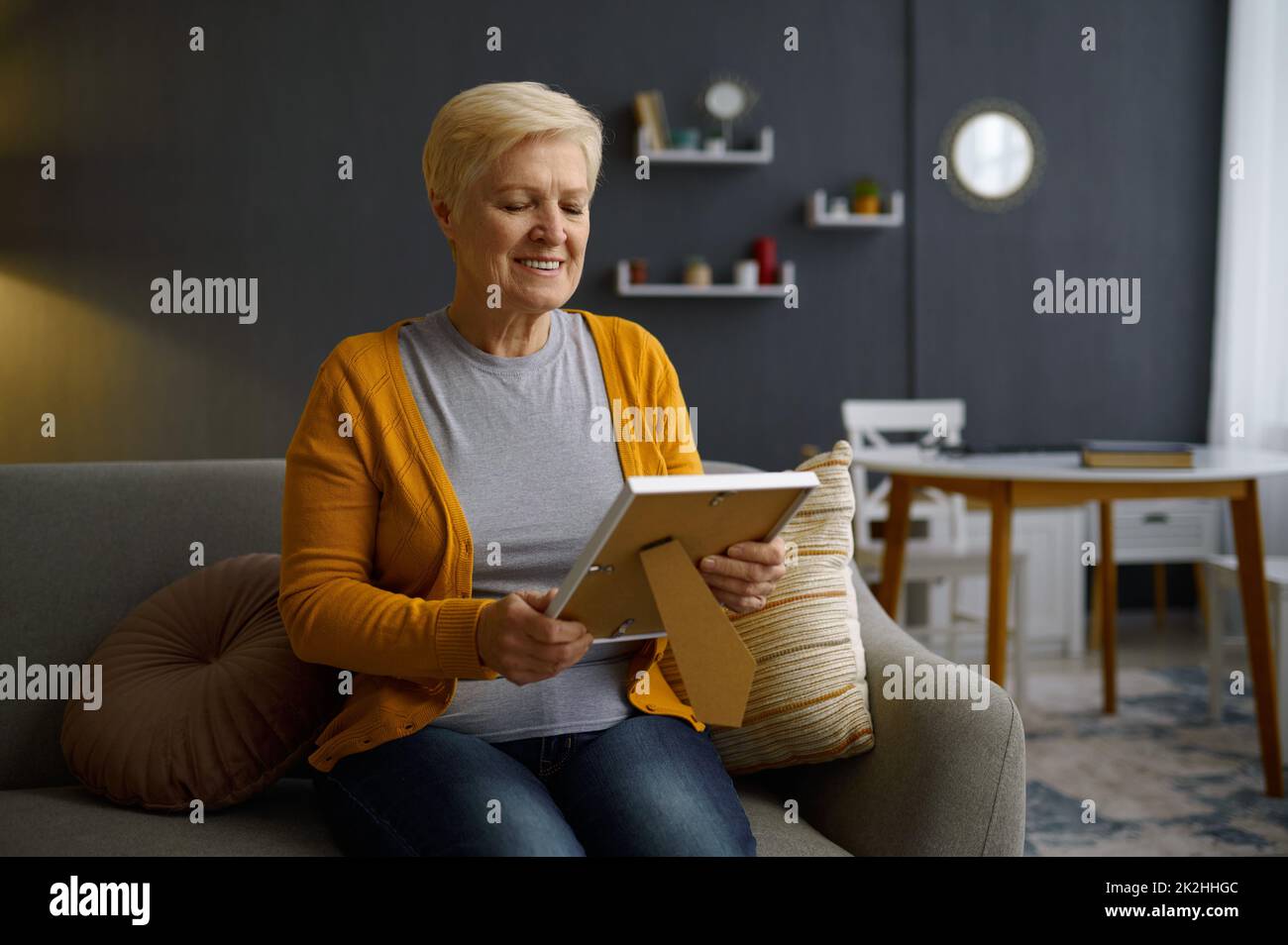 Donna anziana con cornice fotografica a casa Foto Stock