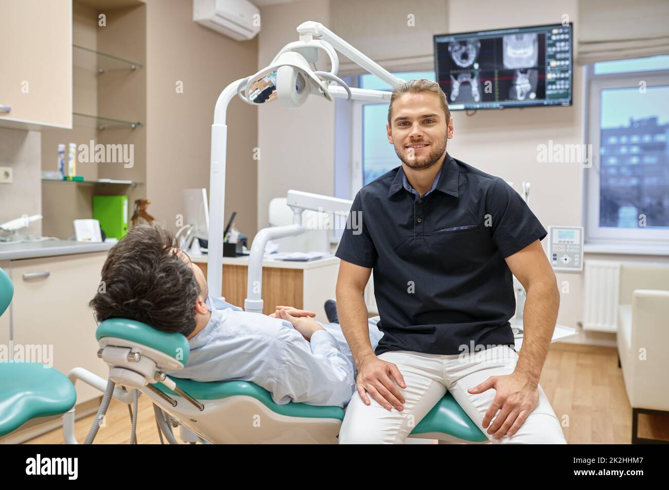 Dentista seduto vicino al paziente in posizione verticale Foto Stock