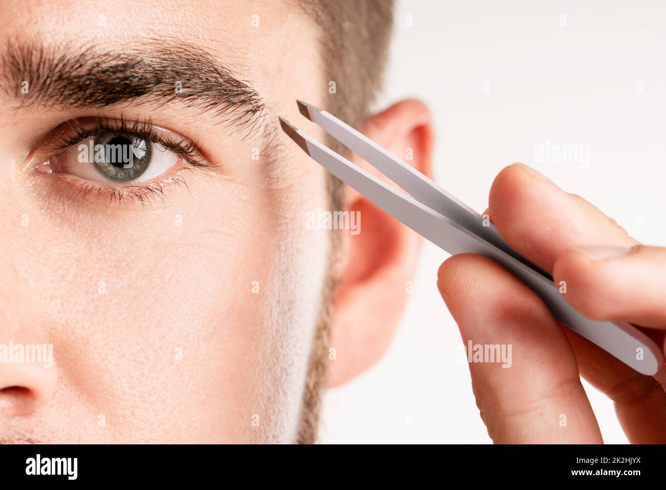 Occhio maschio e pinzette per la cura delle sopracciglia e la correzione della forma Foto Stock