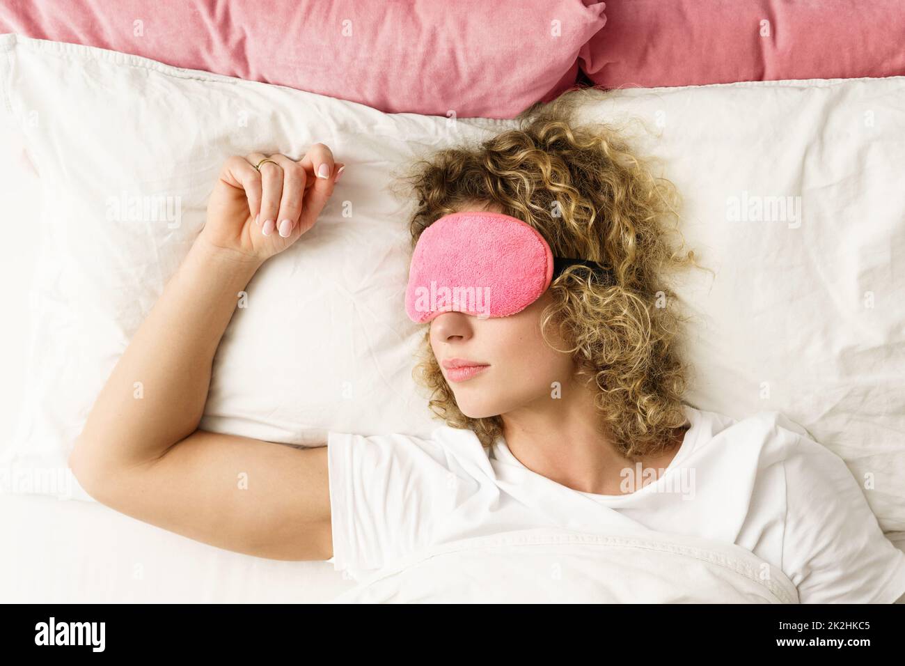 Bella donna che dorme con una bendata rosa sui suoi occhi Foto Stock