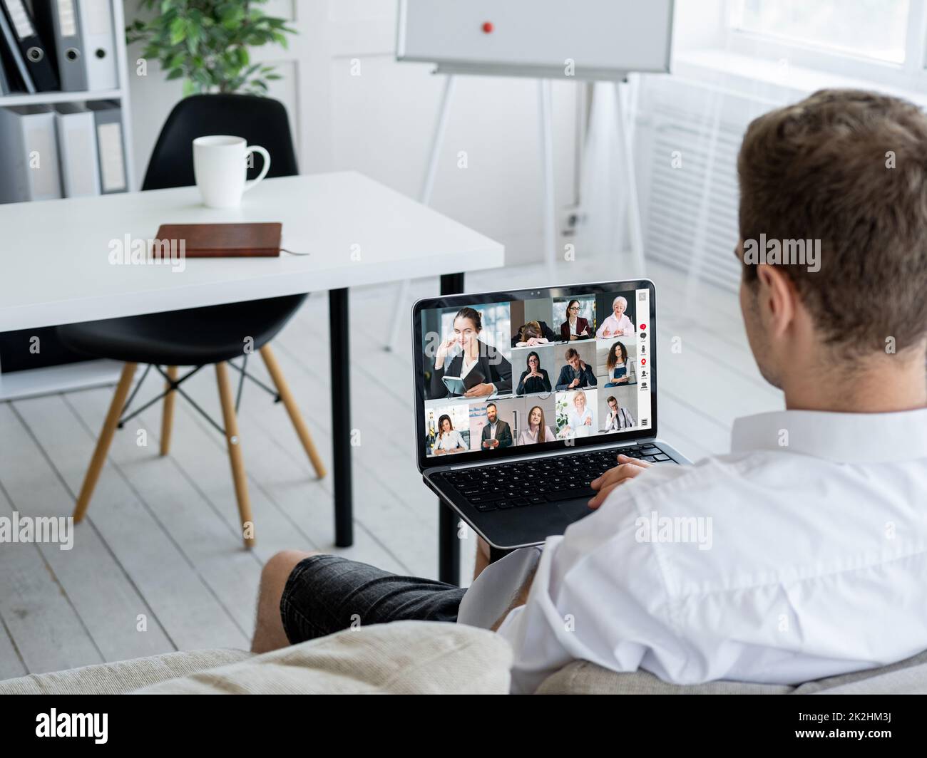 Teleconferenza del team aziendale. Riunione remota. Cooperazione virtuale. Dipendente maschile che utilizza il notebook per lavorare online con i colleghi sullo schermo in offi digitali Foto Stock