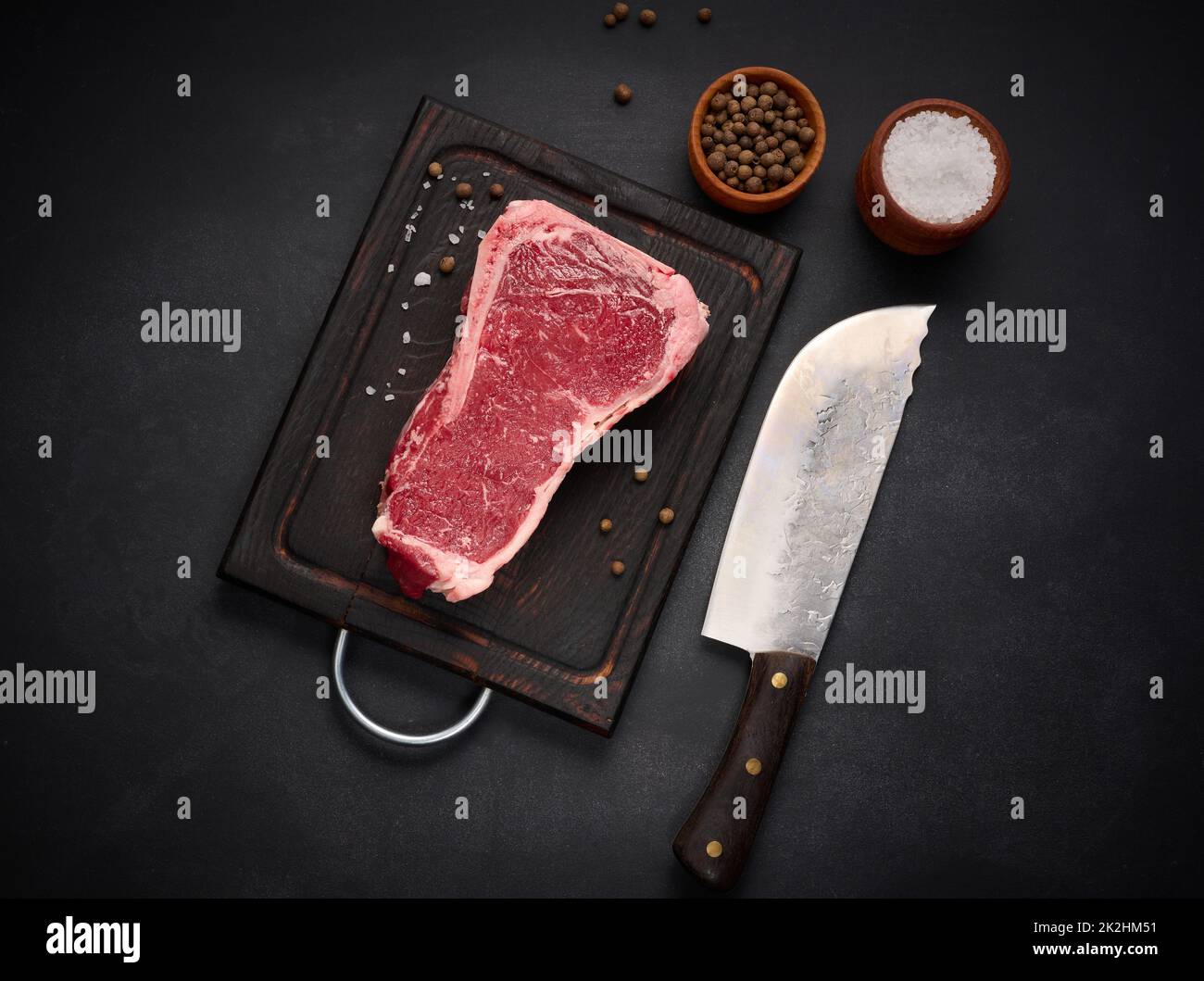 pezzo fresco di carne di manzo crudo, bistecca striploin su sfondo nero, vista dall'alto. Pezzo marmorizzato di carne New York Foto Stock