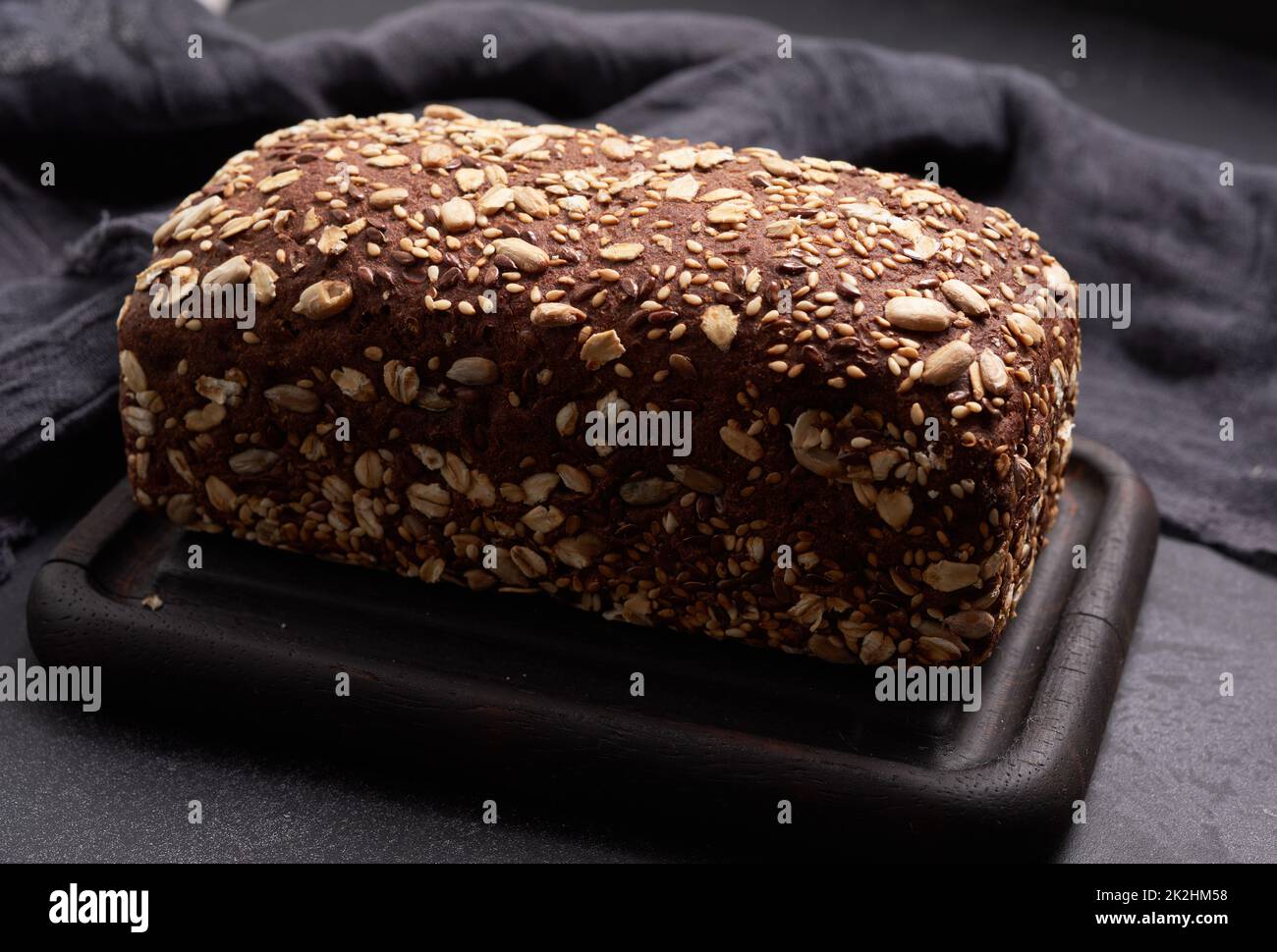 pane di farina di segale quadrata al forno con farinata d'avena su sfondo nero, vista dall'alto Foto Stock