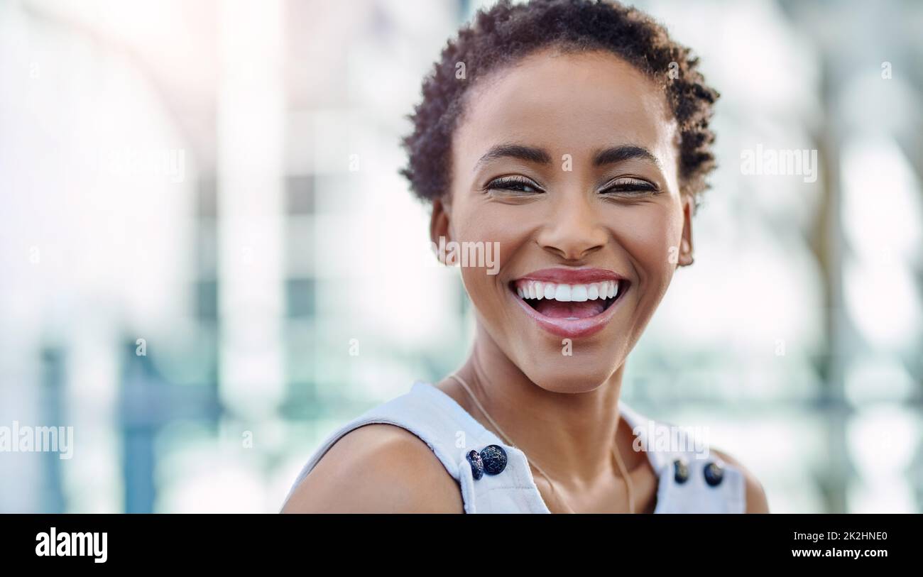 Lavorate sodo e il mondo aziendale vi ricompenserà. Ritratto corto di una giovane donna d'affari attraente sorridente mentre seduto in un posto di lavoro moderno. Foto Stock
