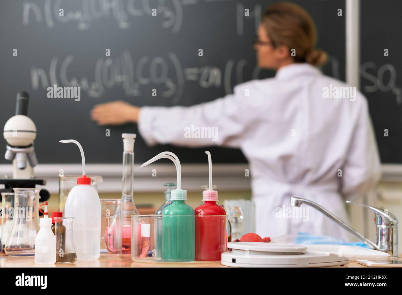 L'insegnante spiega come leggere un'equazione chimica su una lavagna durante una lezione di chimica Foto Stock