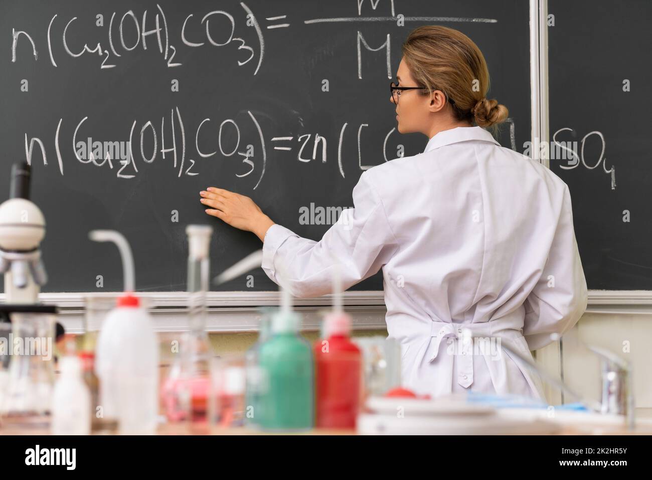 Insegnante di scienziato che spiega come leggere un'equazione chimica durante una lezione di chimica Foto Stock