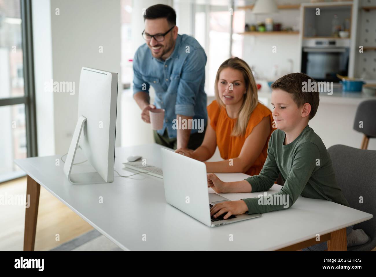 Lavorare da casa con il bambino. I genitori d'affari impegnati lavorano mentre i bambini giocano sul laptop. Foto Stock