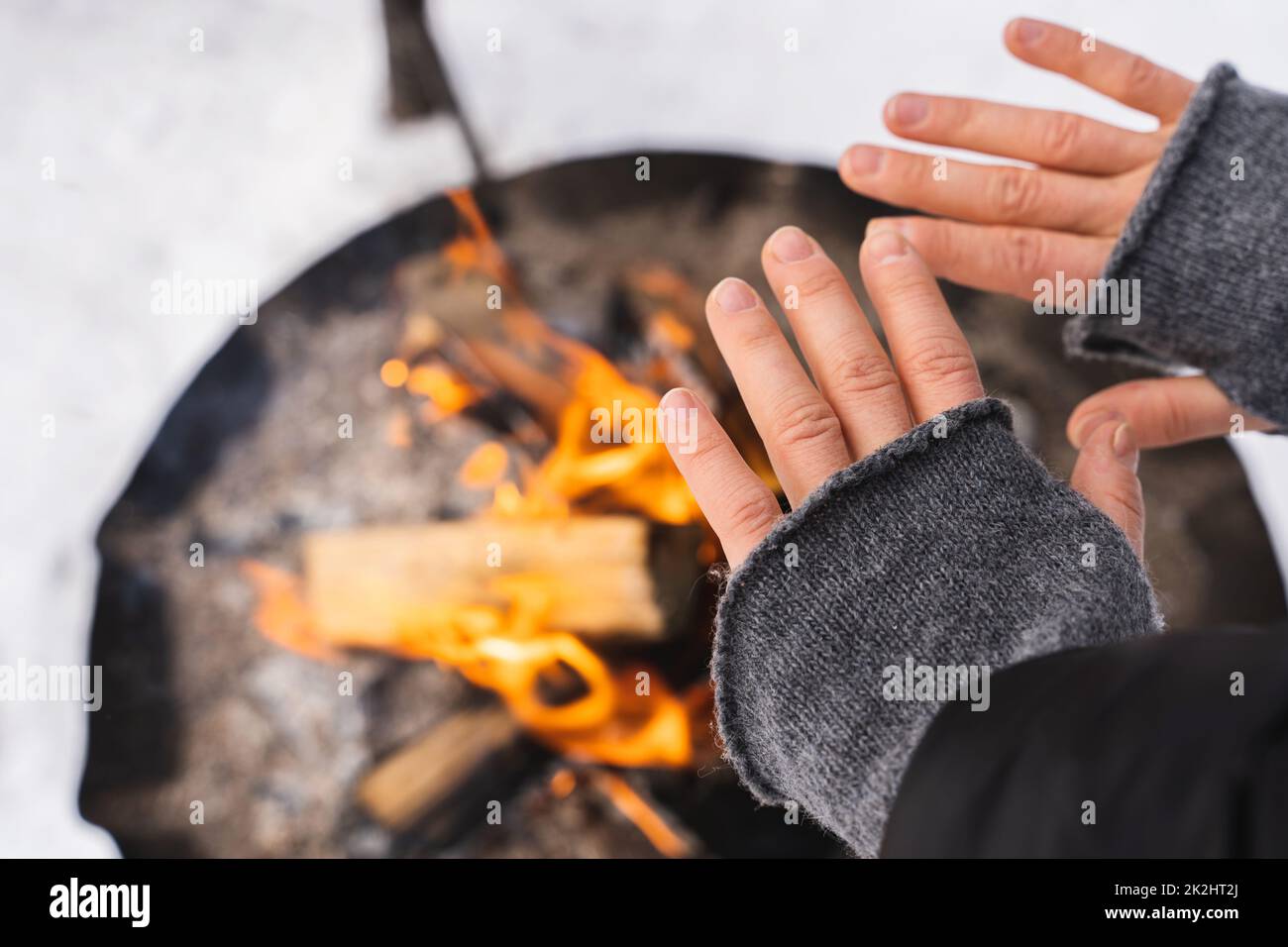 Donna che scalda le mani dalla fossa del fuoco Foto Stock