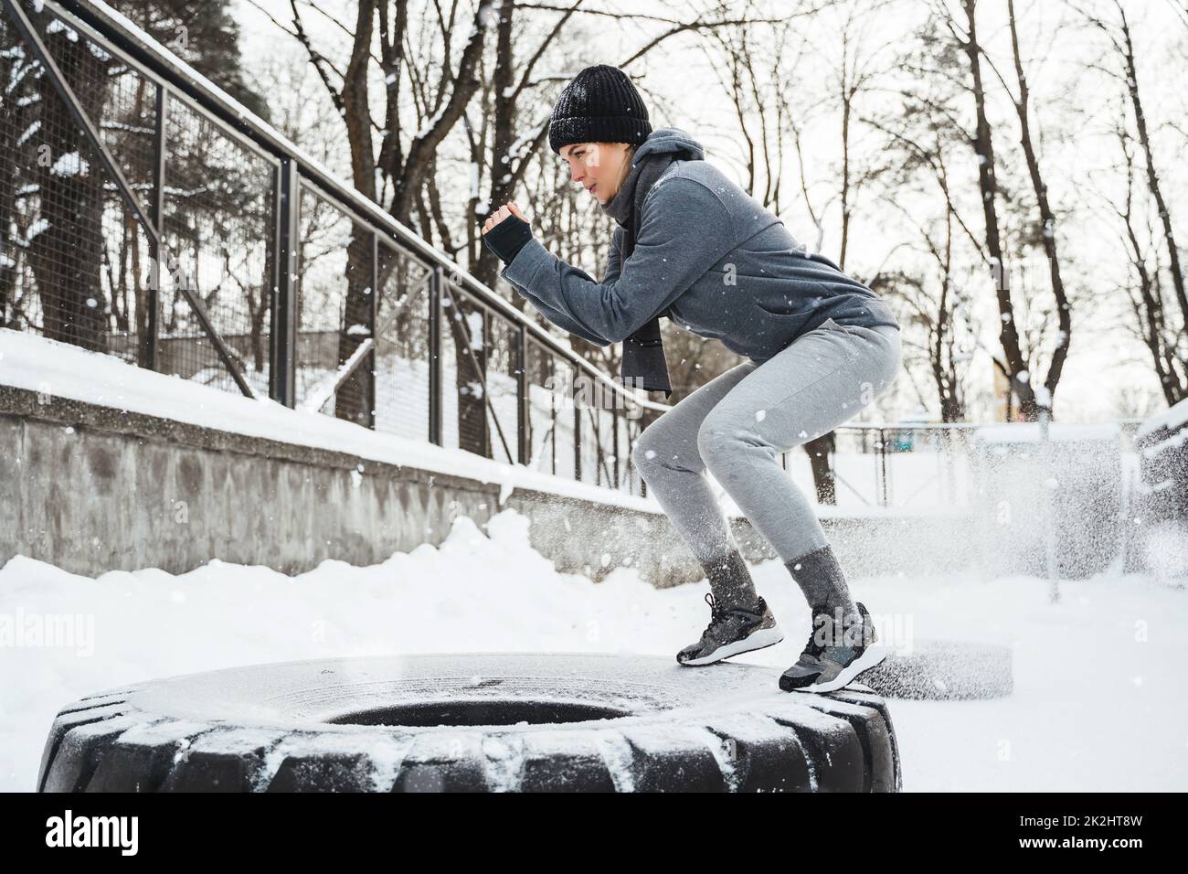 Donna atletica durante il suo allenamento invernale all'aperto con un pneumatico Foto Stock