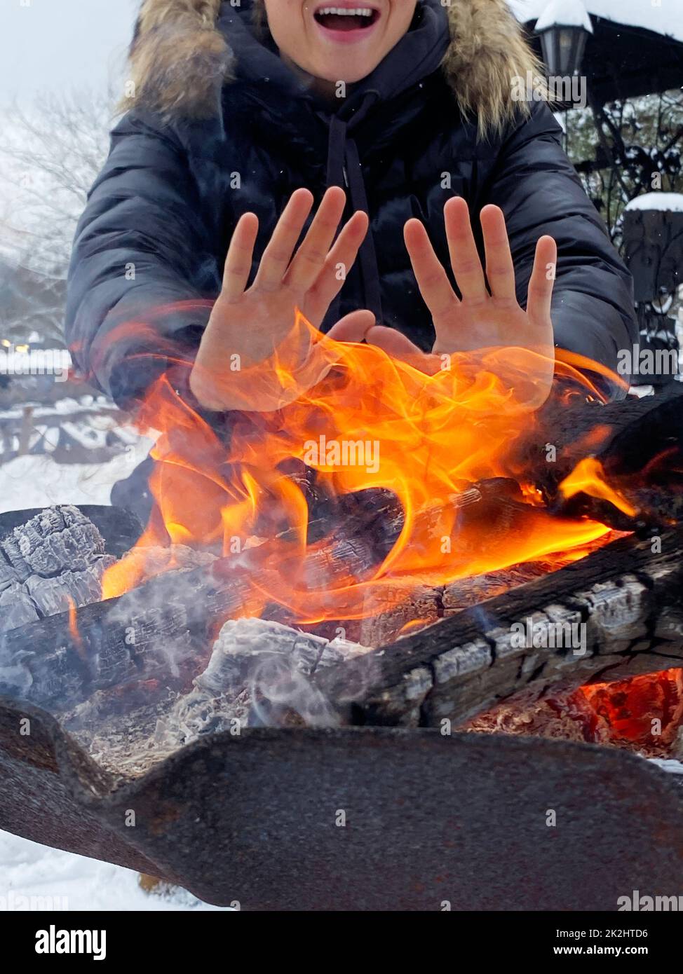 Donna che scalda le mani dalla fossa del fuoco Foto Stock