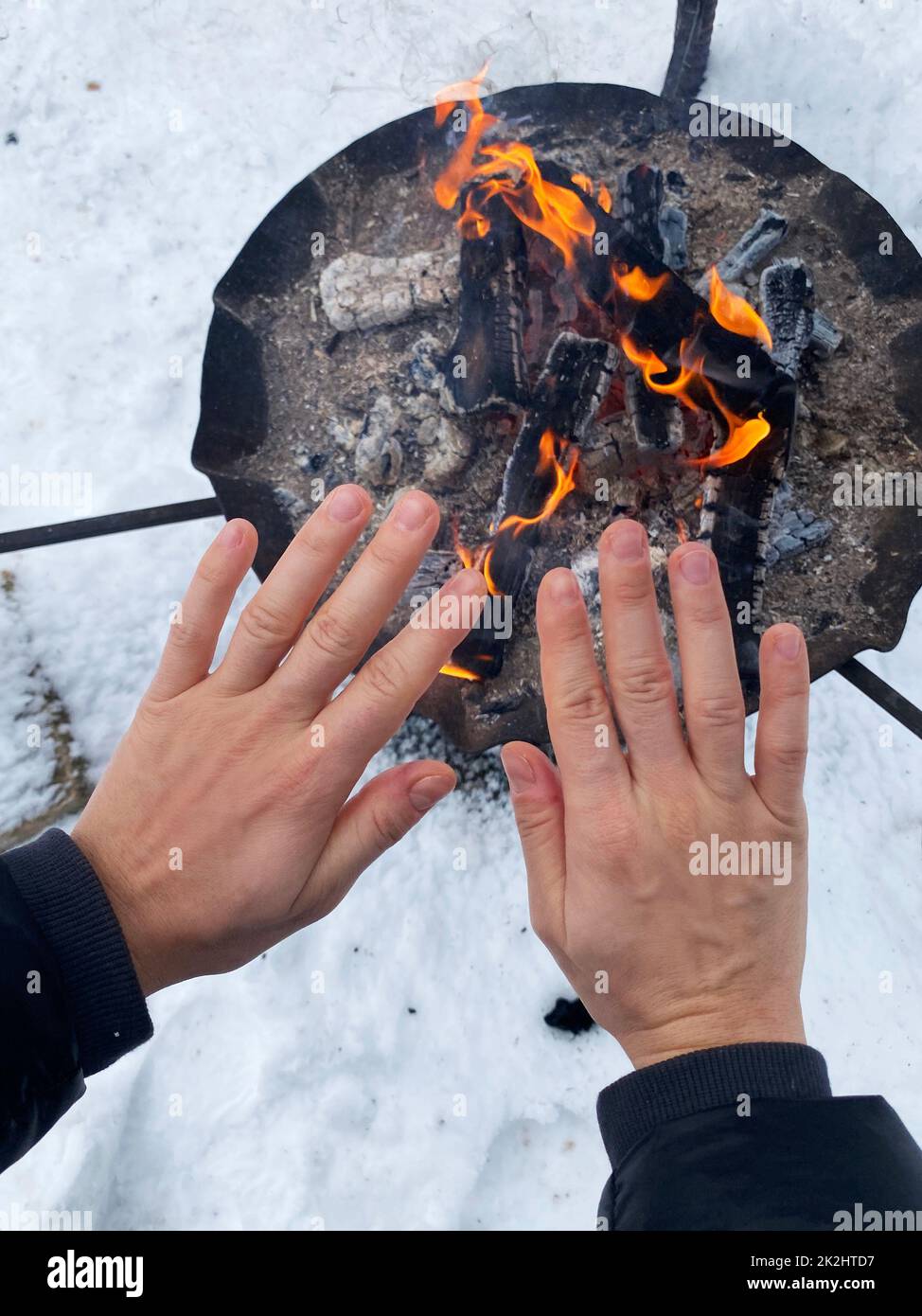 Donna che scalda le mani dalla fossa del fuoco Foto Stock