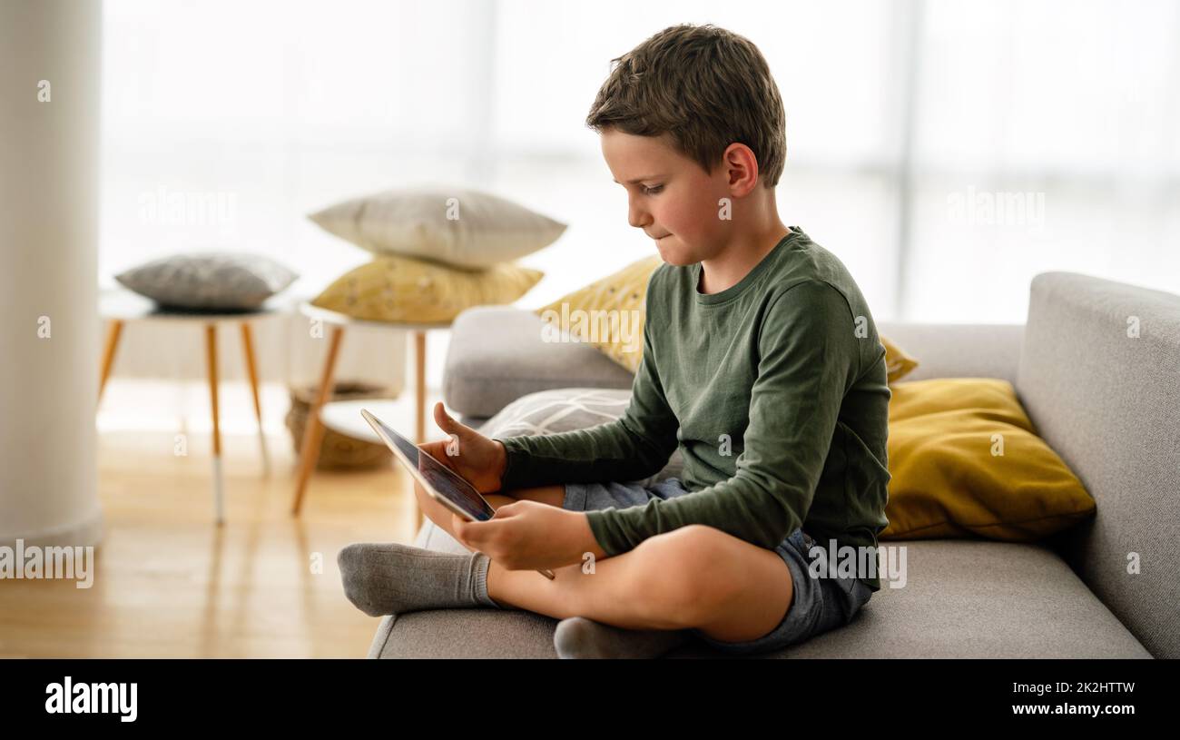 Il bambino sorride mentre gioca con un tablet digitale a casa Foto Stock