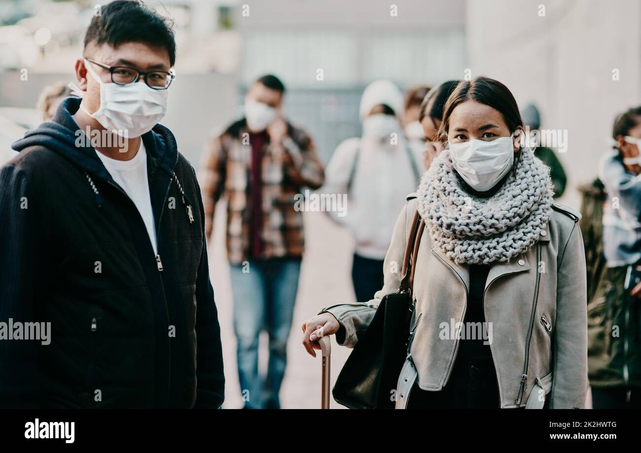 Il turismo assume un nuovo look. Scatto di un giovane uomo e donna che indossa maschere mentre si viaggia in una città straniera. Foto Stock