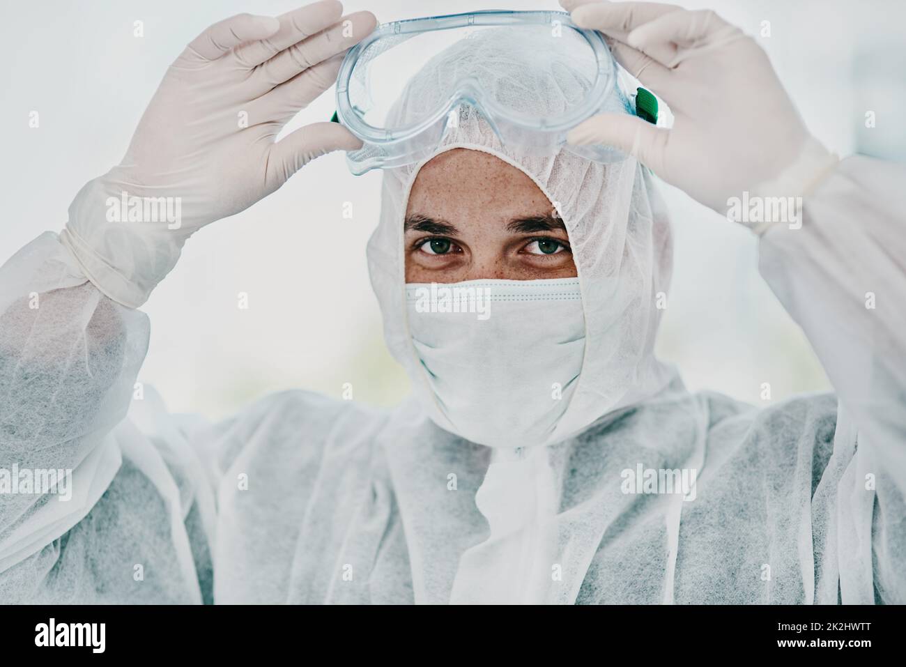 È tempo di annientare questo virus. Scatto di un giovane uomo che mette il suo equipaggiamento protettivo prima del processo di decontaminazione. Foto Stock