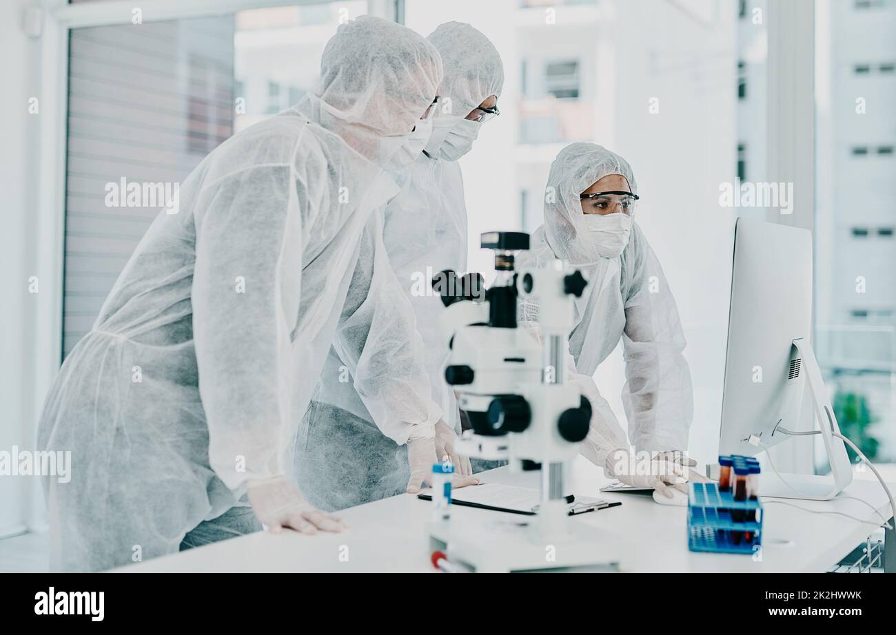 La cura è così vicina. Shot di un gruppo di scienziati in tute nocciole che conduce la ricerca medica in un laboratorio. Foto Stock