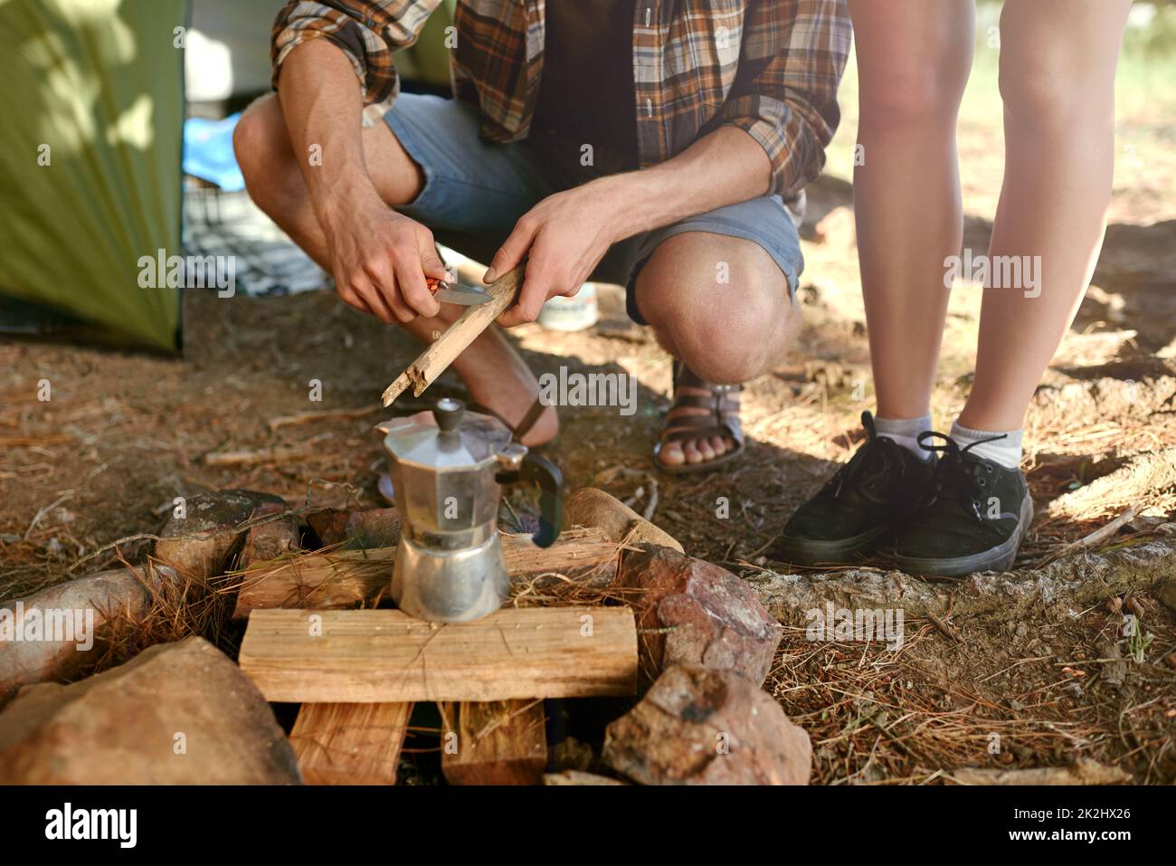 Mettere il caffè del mattino. Shot di campeggiatori che preparano un fuoco per preparare il caffè. Foto Stock