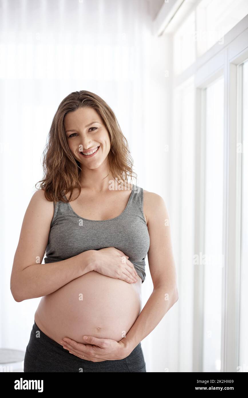 Abbracciando i miei istinti materni. Ritratto corto di una giovane donna incinta in piedi nella sua casa. Foto Stock