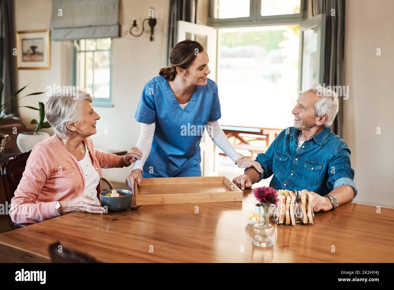 Spero che la colazione sia buona. Shot di una giovane infermiera che controlla su una coppia anziana durante la prima colazione in una casa di cura. Foto Stock