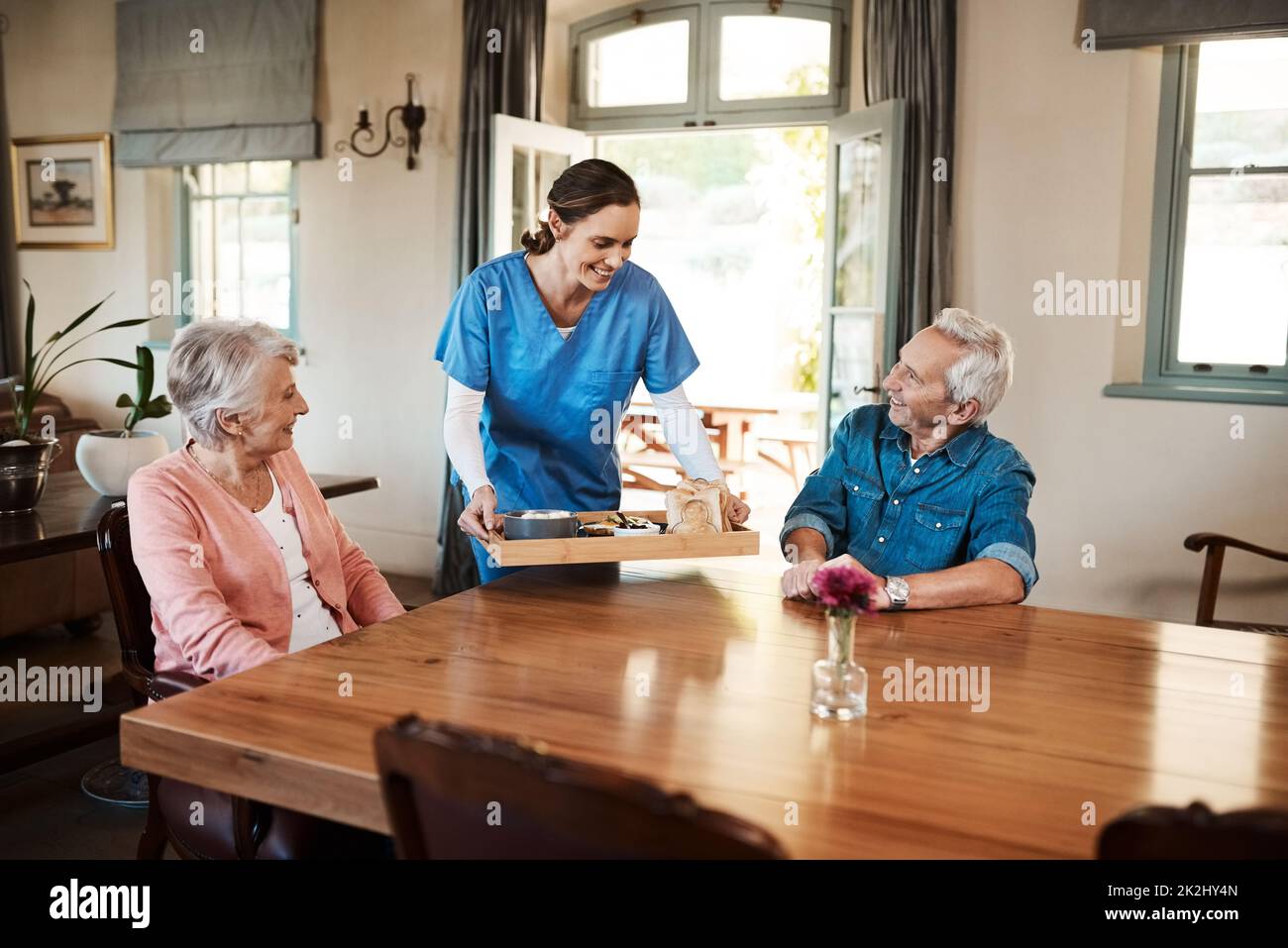 Viene servita la prima colazione. Shot di una giovane infermiera che controlla su una coppia anziana durante la prima colazione in una casa di cura. Foto Stock