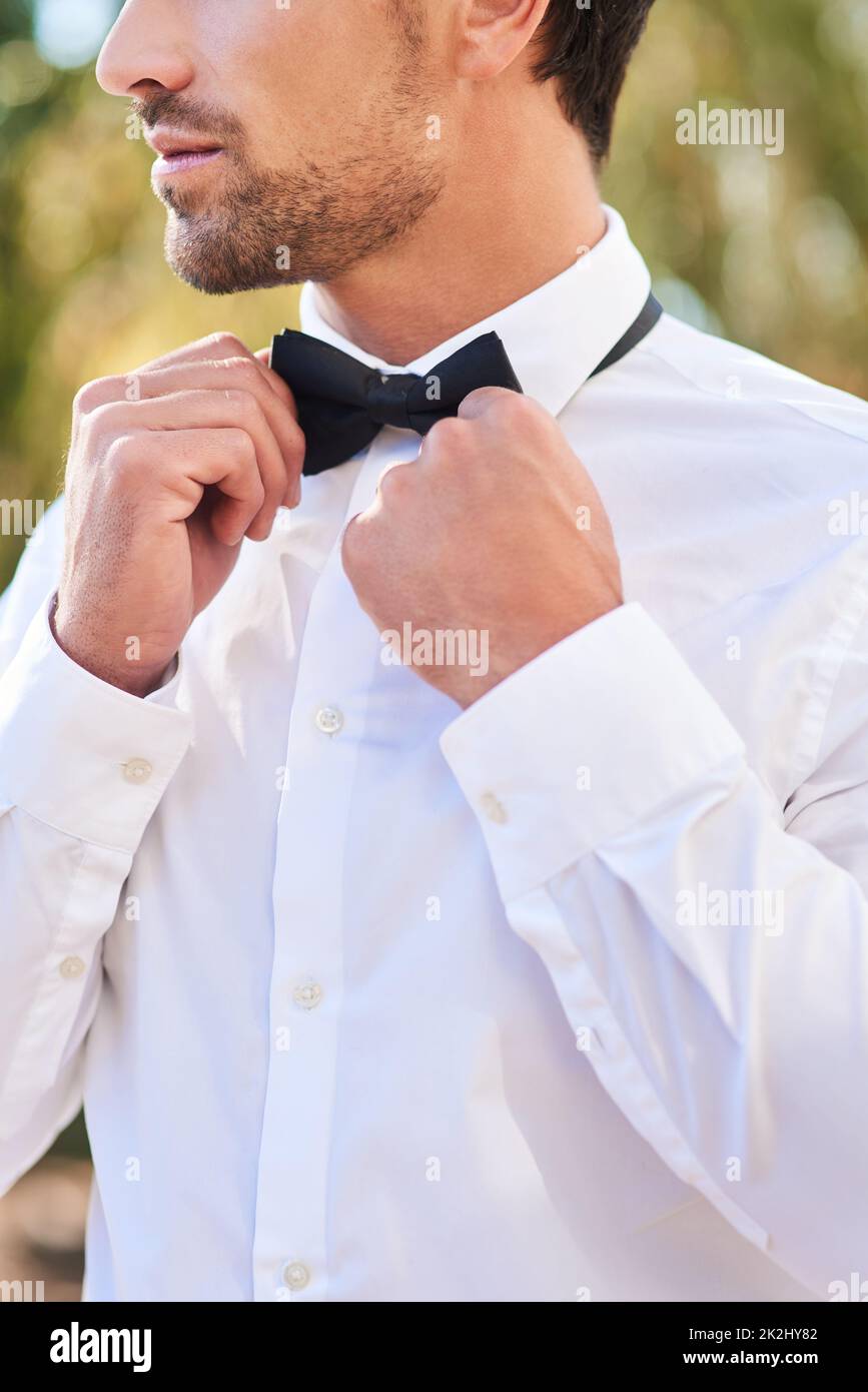 Ora sono pronto. Scatto corto di un giovane sposo irriconoscibile che mette su un bowtie mentre in piedi all'aperto il suo giorno di nozze. Foto Stock