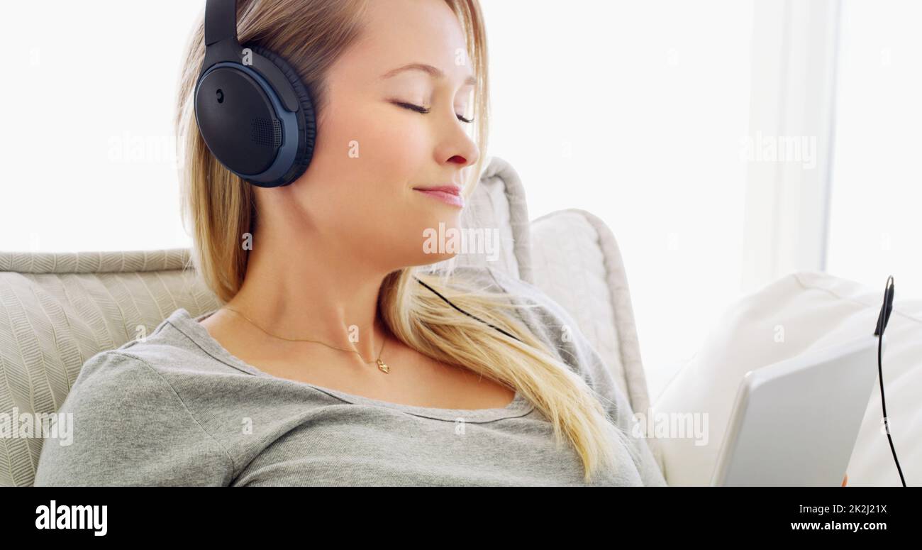 Ascoltare la musica la calmava sempre. Scatto di una giovane donna attraente che ascolta la musica con le cuffie a casa. Foto Stock