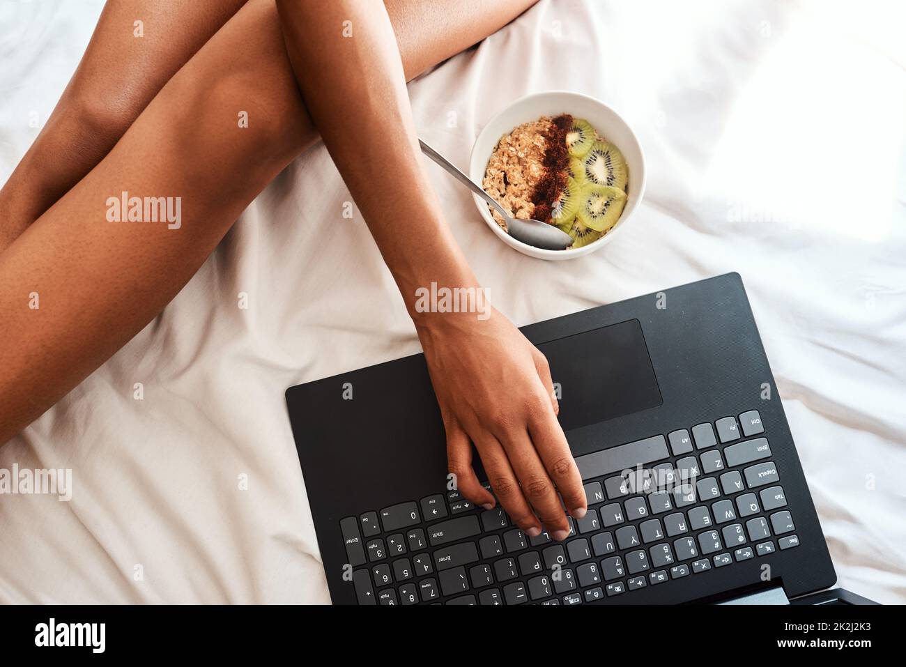Ho avuto questa idea di colazione online. Scatto corto di una donna irriconoscibile seduta sul suo letto con il suo laptop e una ciotola di avena. Foto Stock