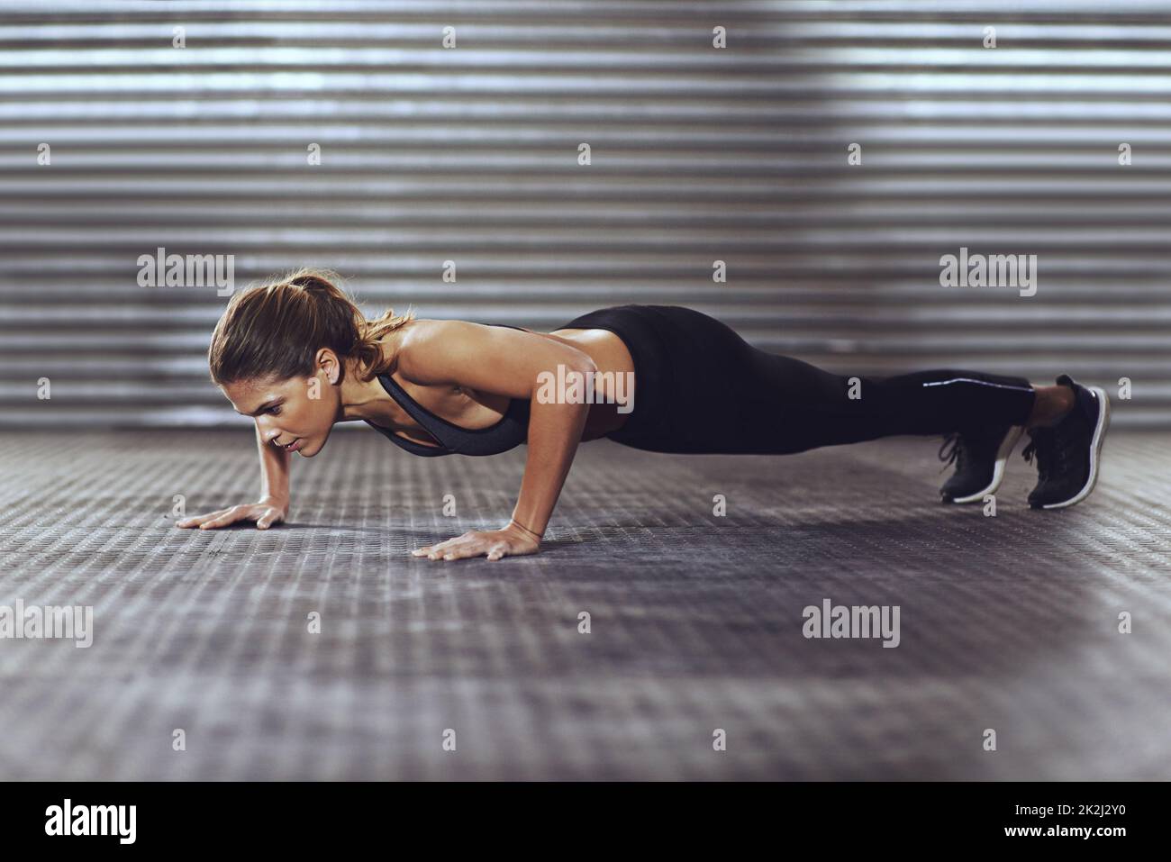 Sia la vostra motivazione migliore. Shot di una giovane donna che fa push-up in palestra. Foto Stock