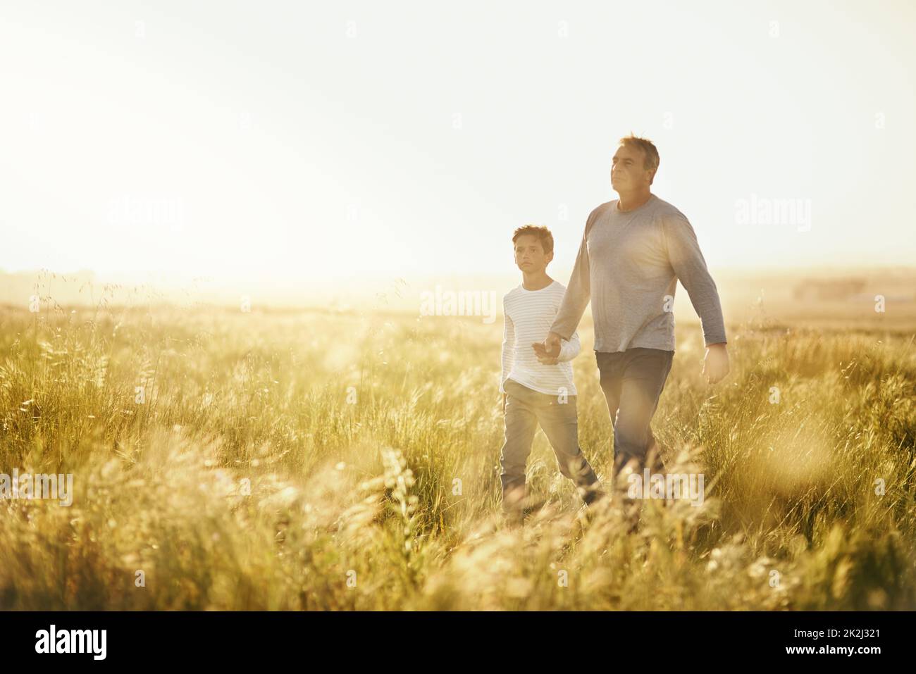 Mostrargli la bellezza della natura. Colpo di un uomo che prende suo figlio per una passeggiata su un campo aperto. Foto Stock