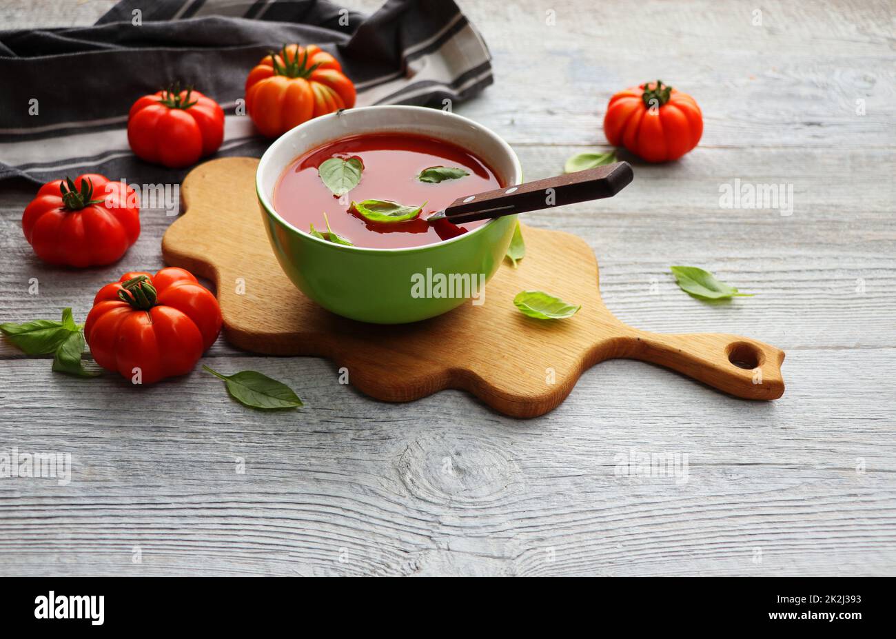 Una ciotola di gazpacho fresco, zuppa di pomodoro fredda con foglie di basilico su sfondo grigio Foto Stock